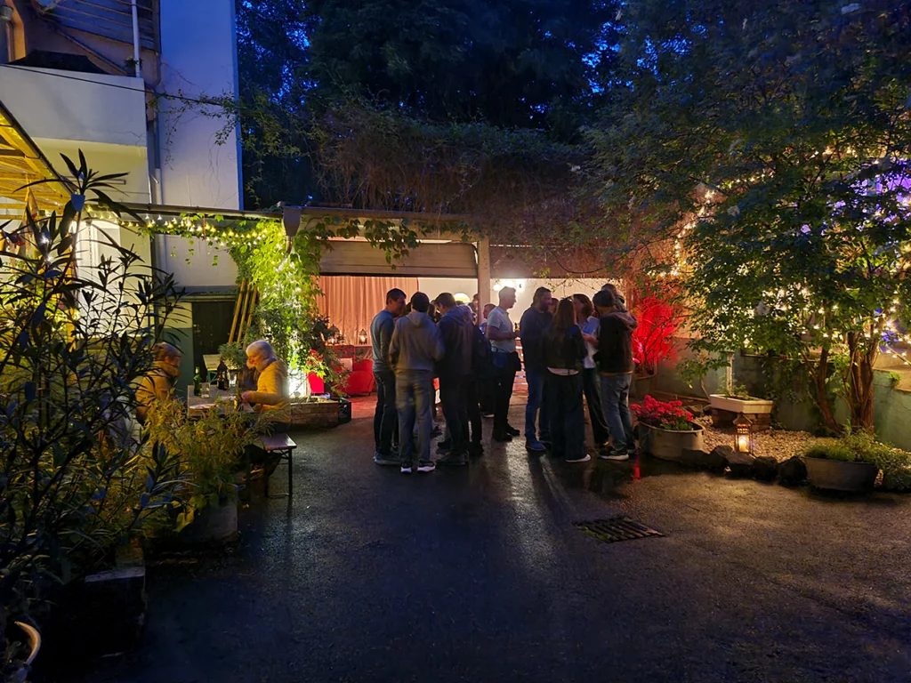 Eine vergnügte Gesellschaft steht im Innenhof des Hofkontors. Die grünen Pflanzen sind mit bunten farben beleuchtet. Die Stimmung ist sehr gemütlich.